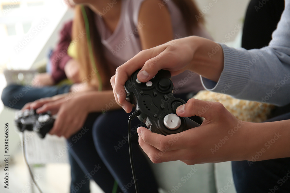 Teenagers playing video games at home, closeup