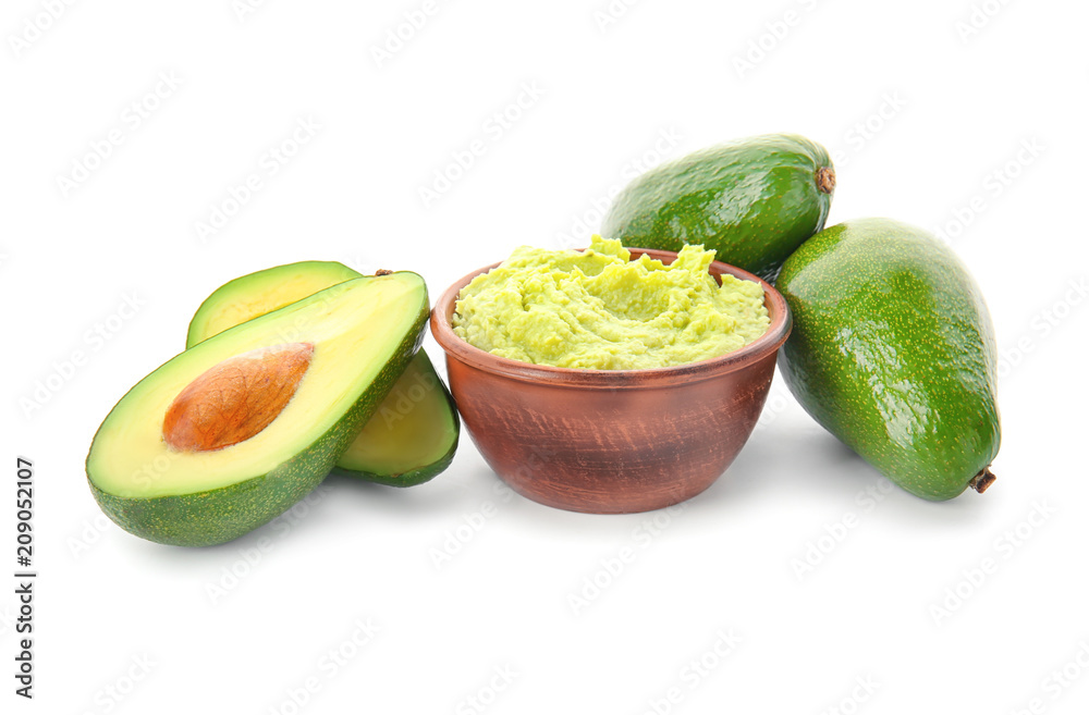 Bowl with tasty guacamole and ripe avocados on white background