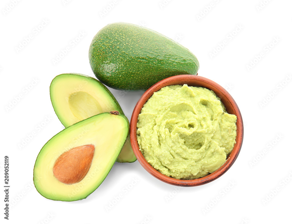 Bowl with tasty guacamole and ripe avocados on white background