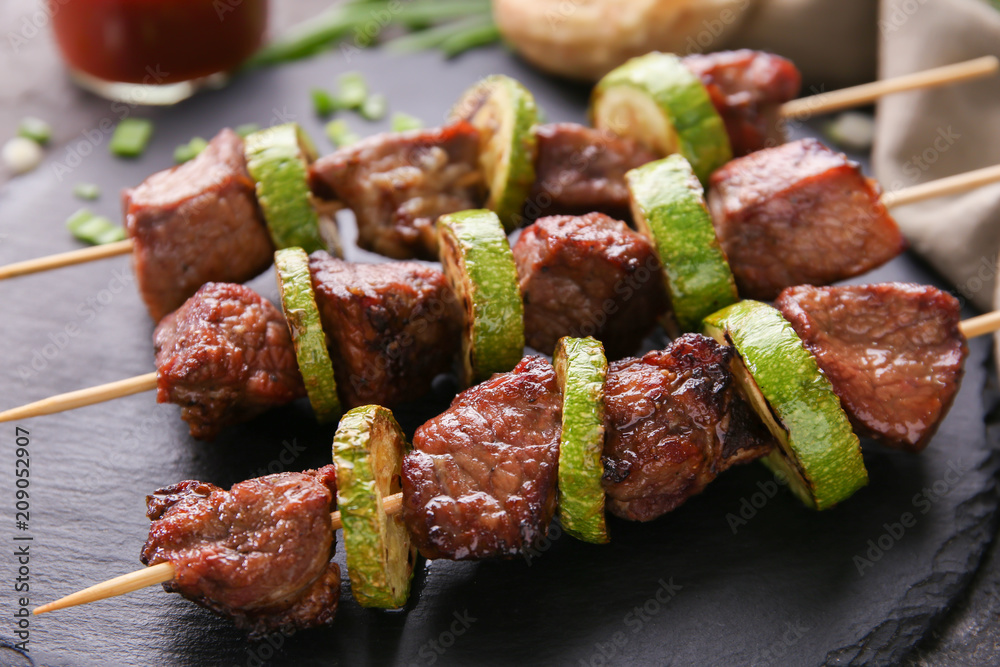 Barbecue skewers with juicy meat and squash on slate plate