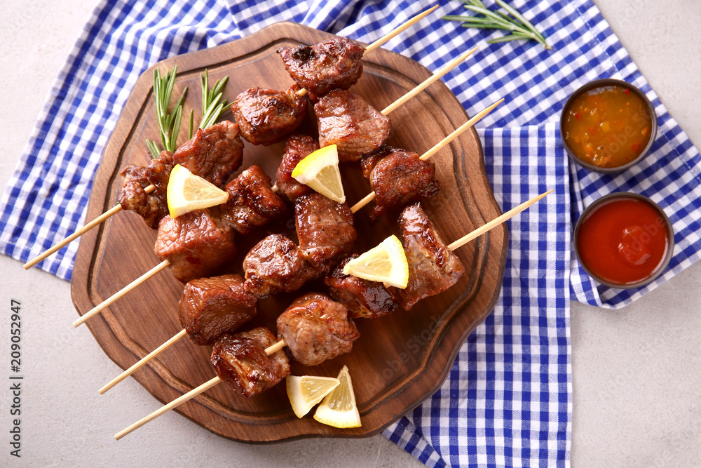 Barbecue skewers with juicy meat on wooden board