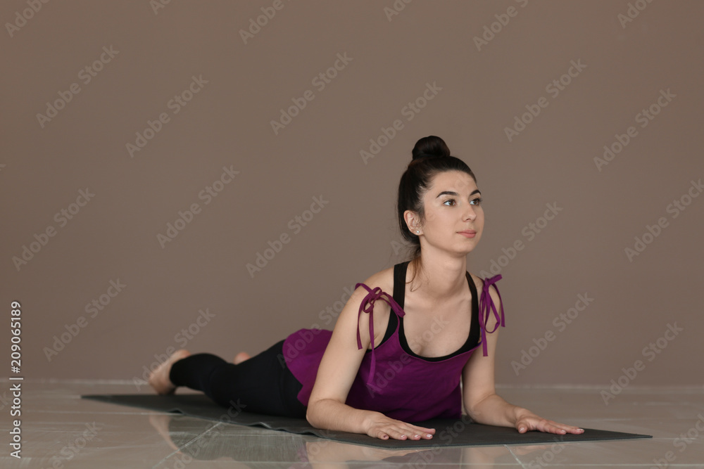 Young woman practicing yoga near color wall