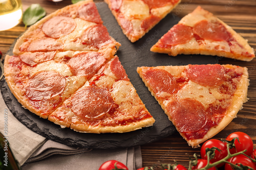 Slate plate with pieces of pepperoni pizza on table