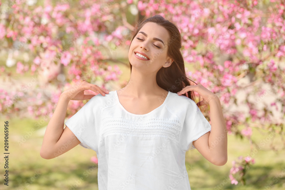 春日公园里盛开的树旁美丽的年轻女子