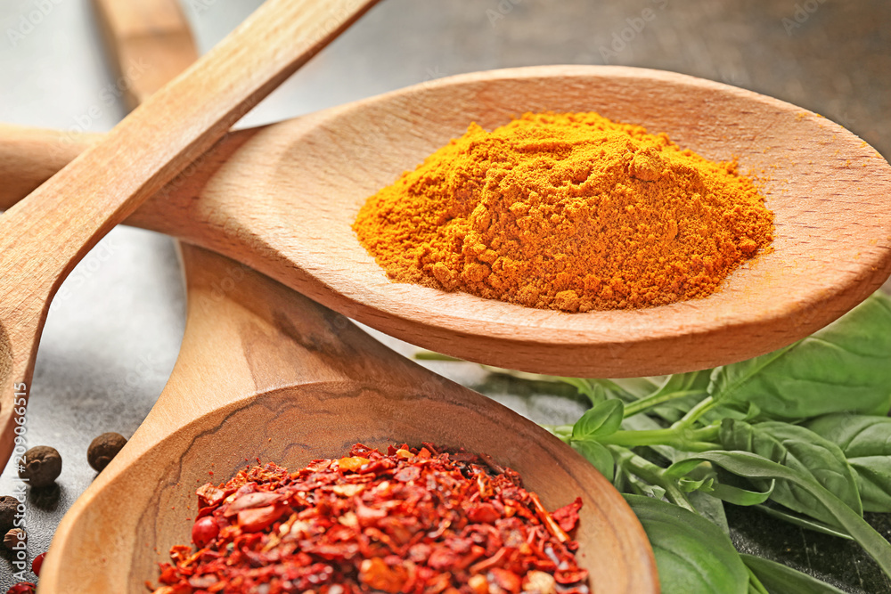 Wooden spoons with different spices on table, closeup