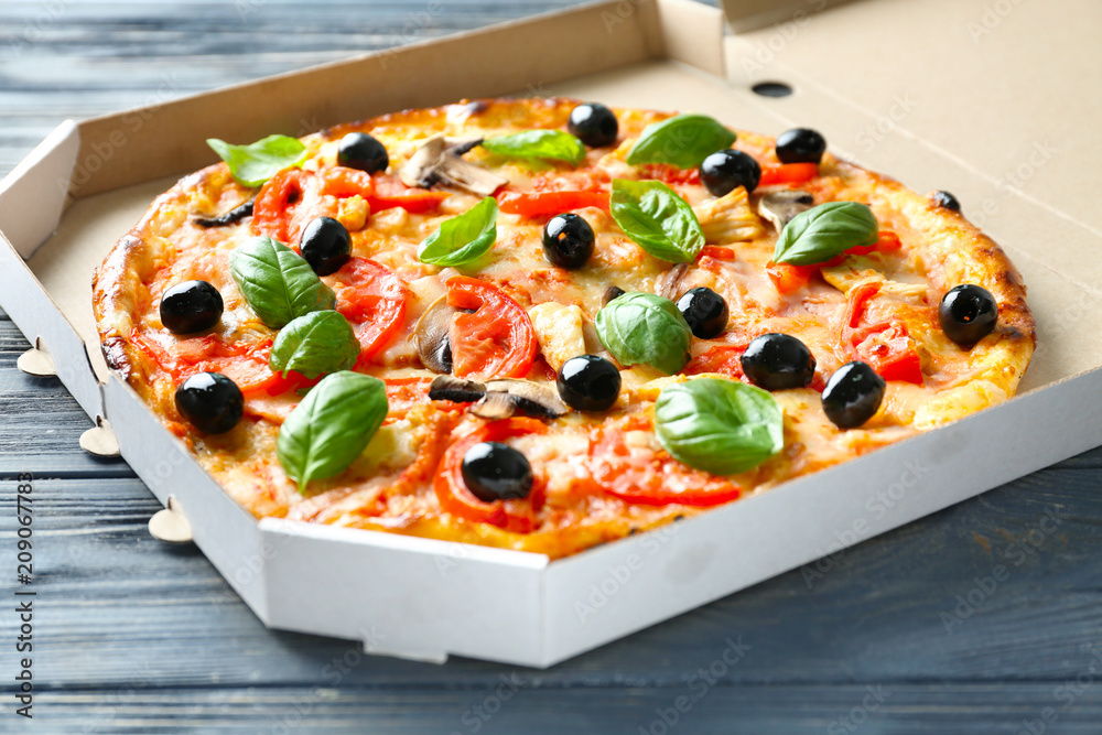 Box with tasty Italian pizza on wooden table