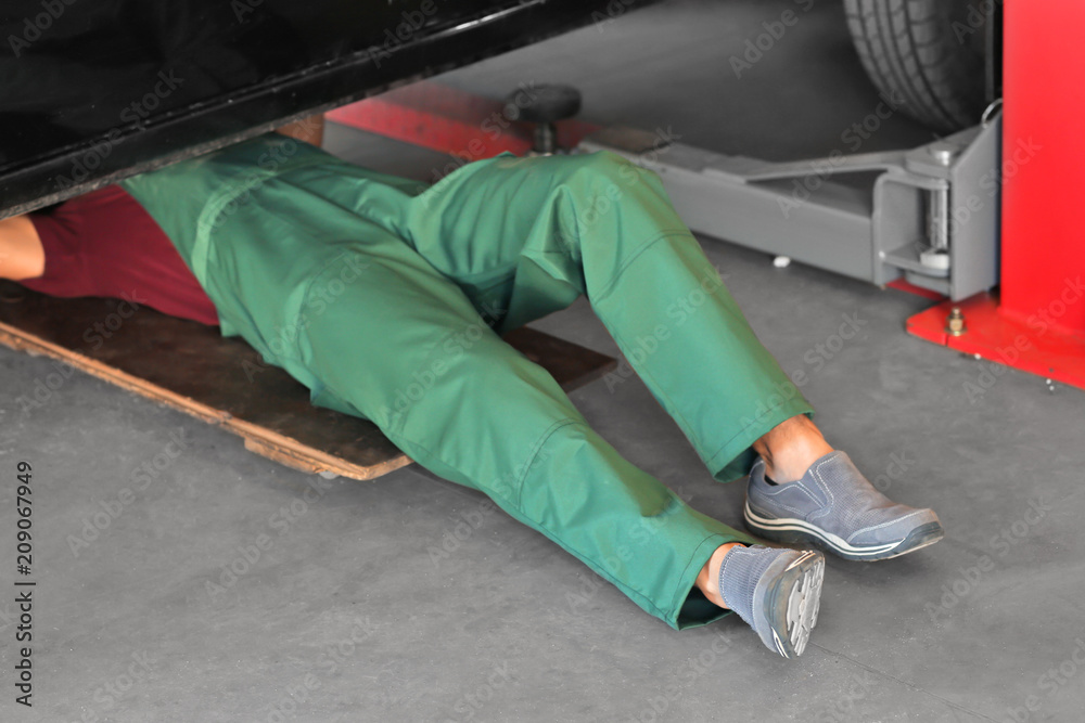 Auto mechanic repairing car in service center