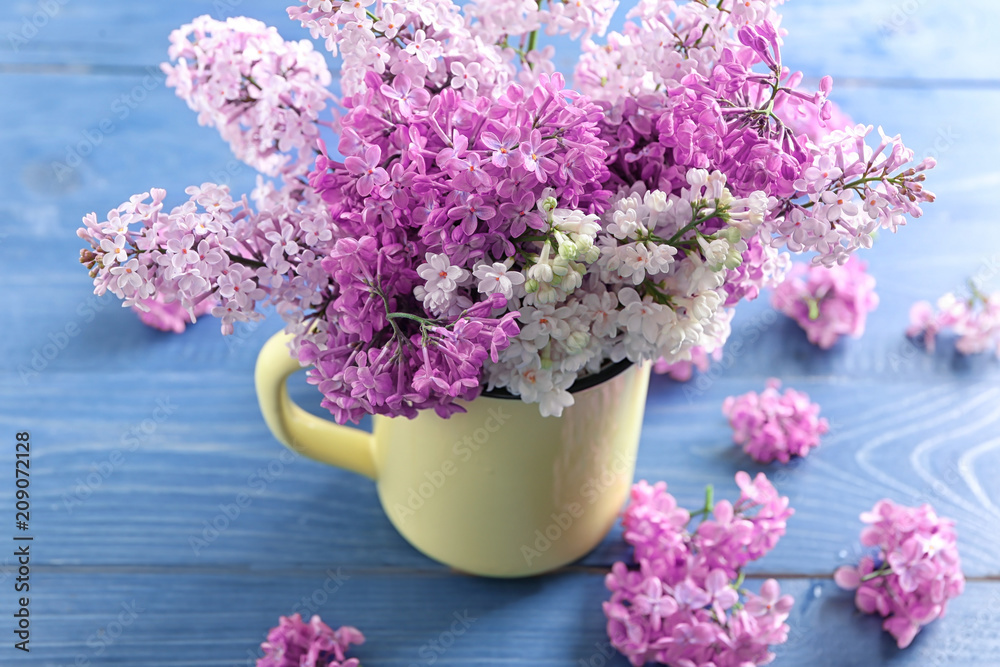 Cup with beautiful blossoming lilac on wooden background