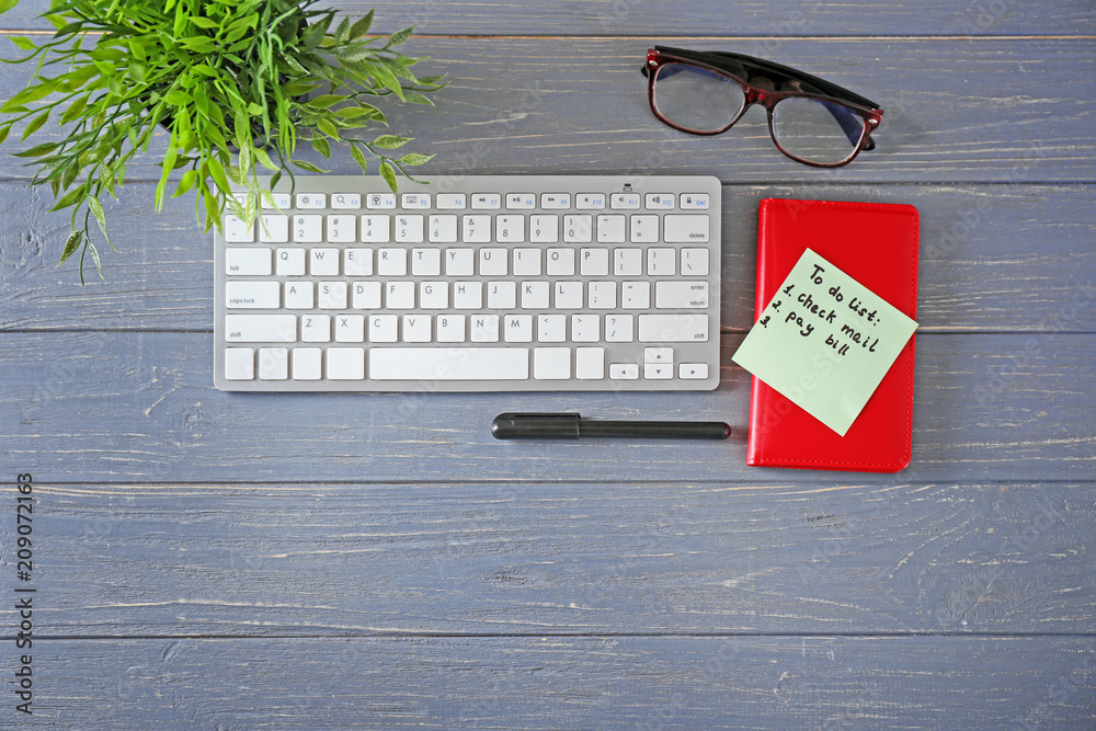 To-do list with computer keyboard on wooden background