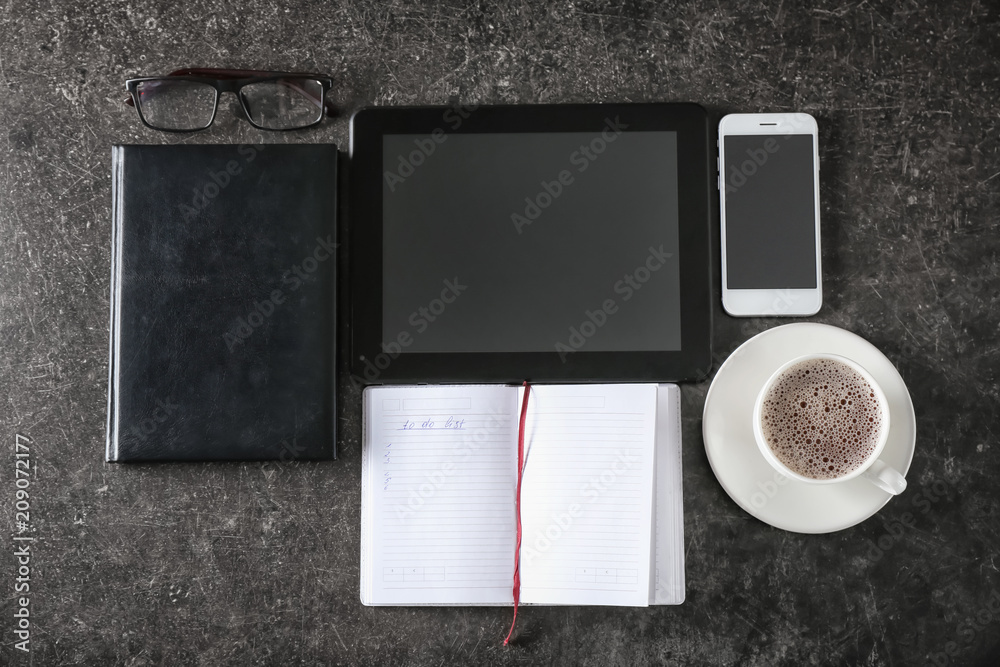 Composition with empty to-do list, gadgets and cup of coffee on grey background