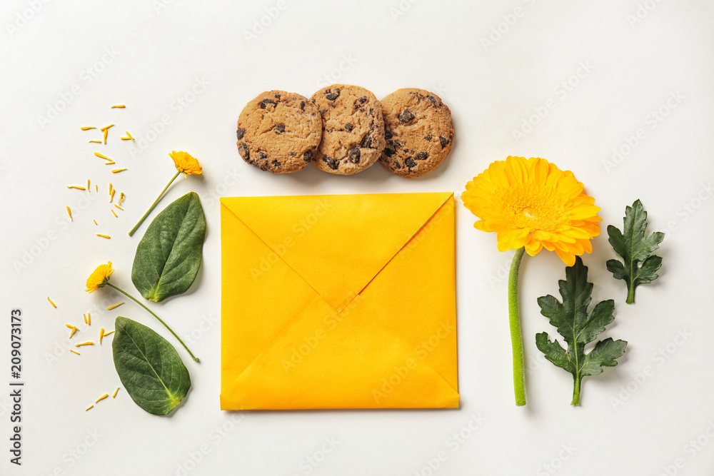 Flat lay composition with flowers, cookies and envelope on white background