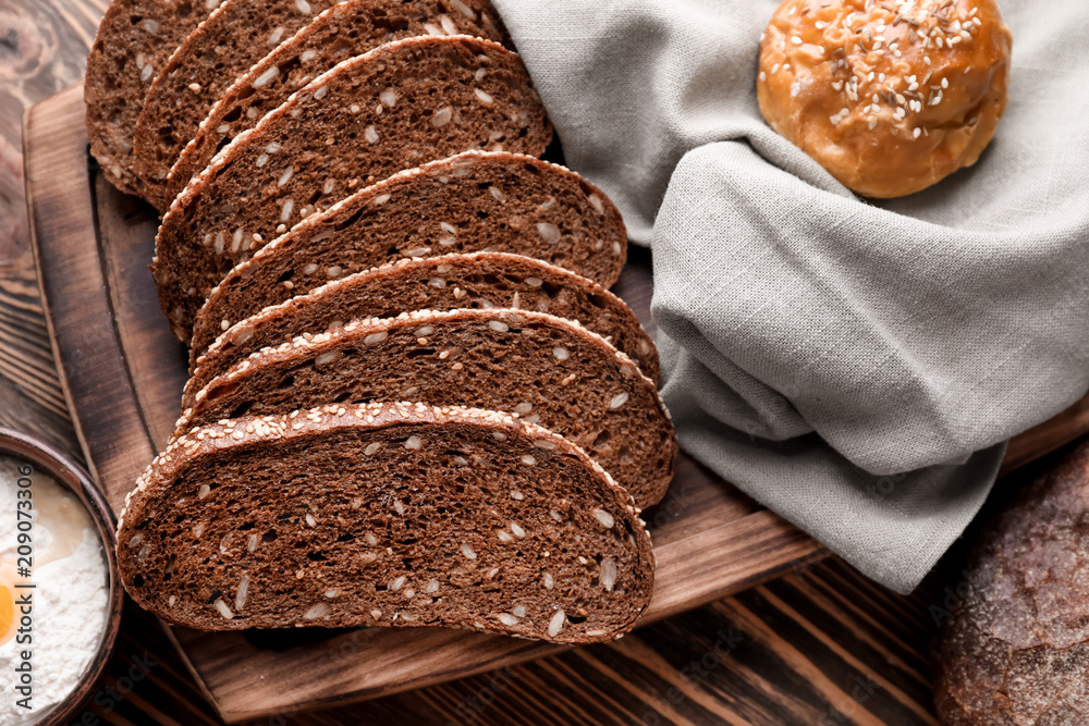 Wooden plate with sliced fresh tasty bread on table