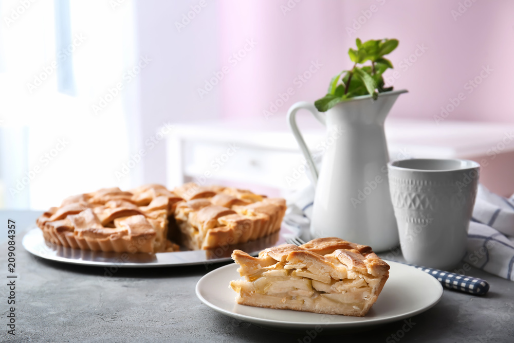 Plate with piece of delicious apple pie on table