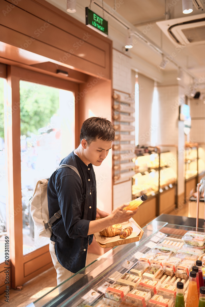 当地面包店的帅哥拿着一盘面包或馅饼买甜点