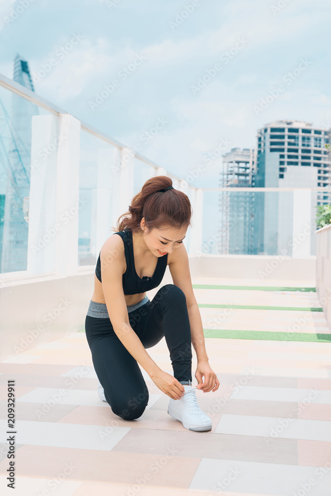 运动女性。穿着运动服的年轻美女夏季肖像全身系鞋带