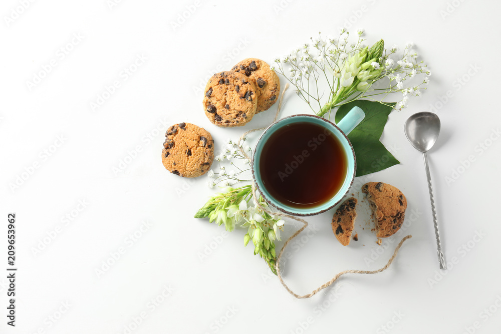 美丽的平躺构图，白底上有一杯茶、鲜花和饼干