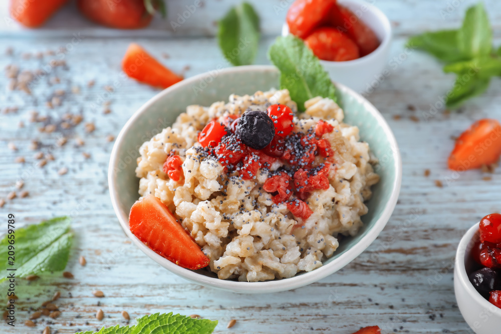 Bowl with tasty oatmeal and fresh berries on wooden table