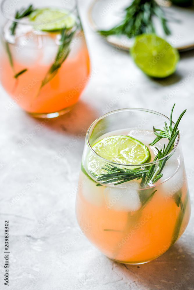 glass of fresh juice with lime and rosemary on stone table backg