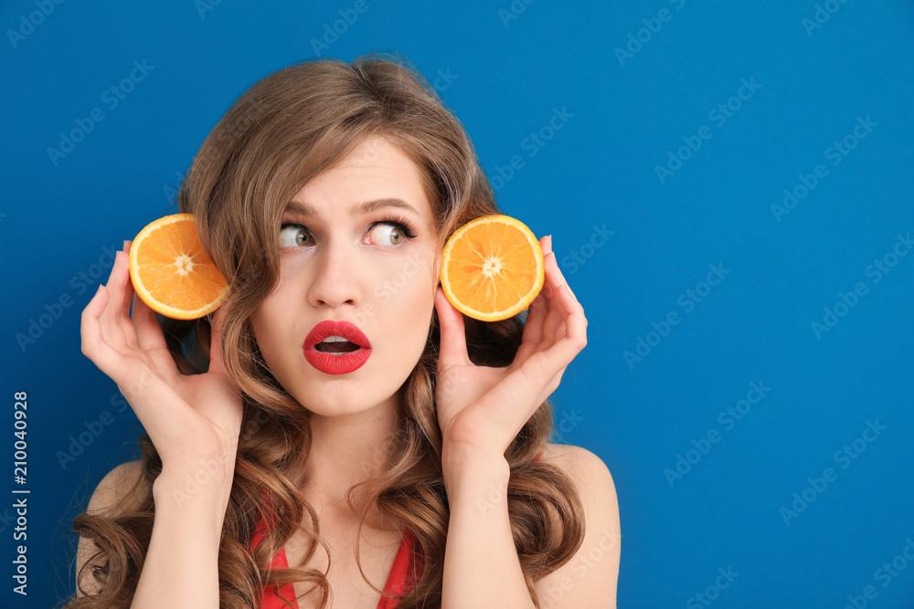 Funny young woman with halves of orange on color background