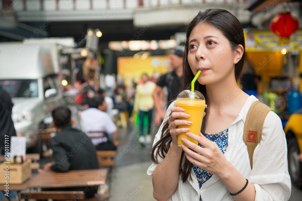 在街上喝芒果汁的女人