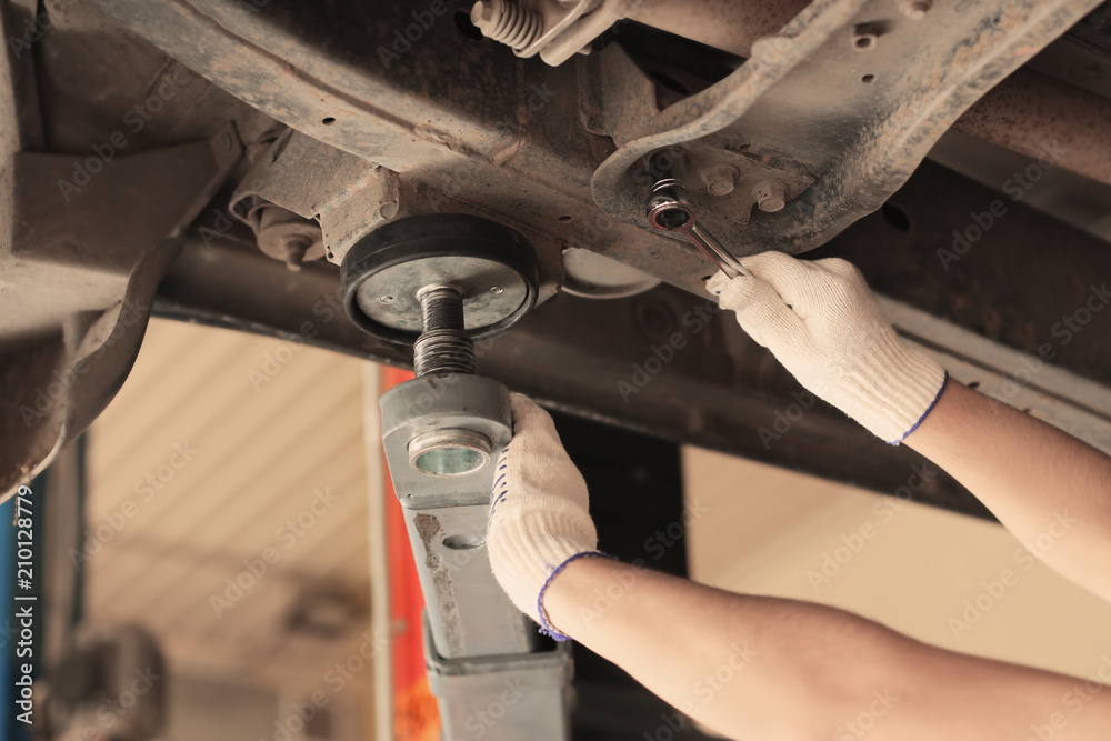 Auto mechanic repairing car in service center, closeup