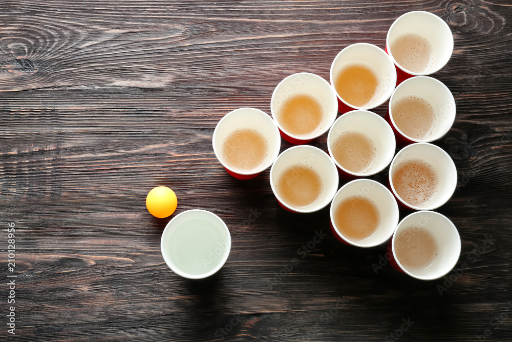 Cups and ball for beer pong on wooden table