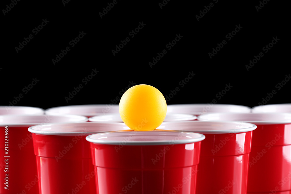 Cups and ball for beer pong on dark background