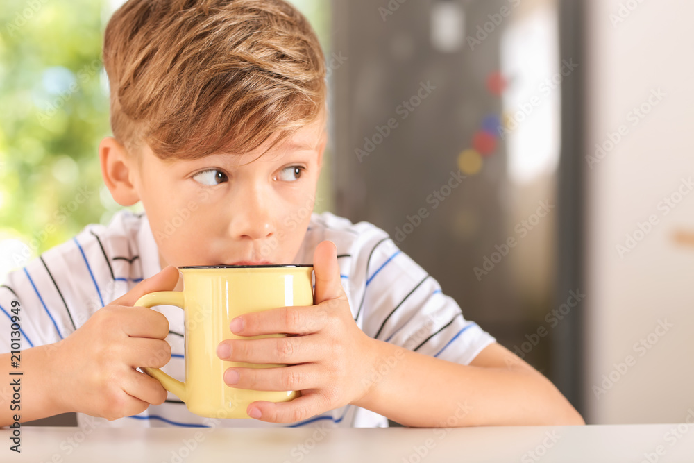 Cute little boy with cup of hot cocoa drink at home