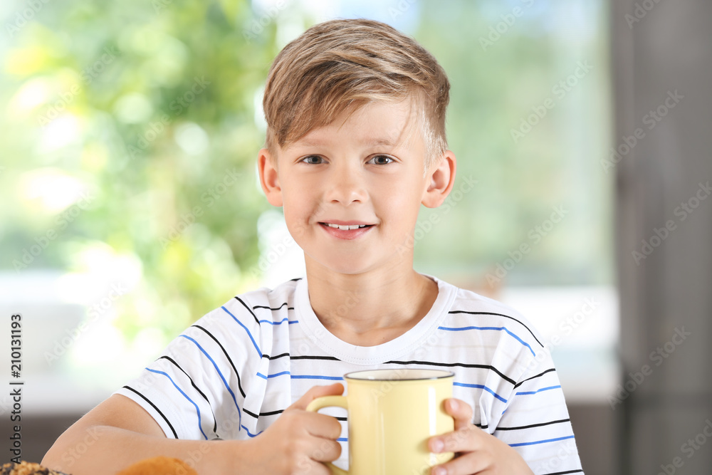 Cute little boy with cup of hot cocoa drink at home