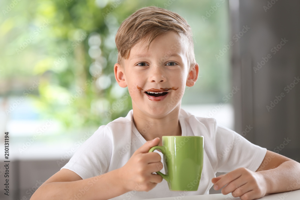 桌上有一杯热可可饮料的可爱小男孩