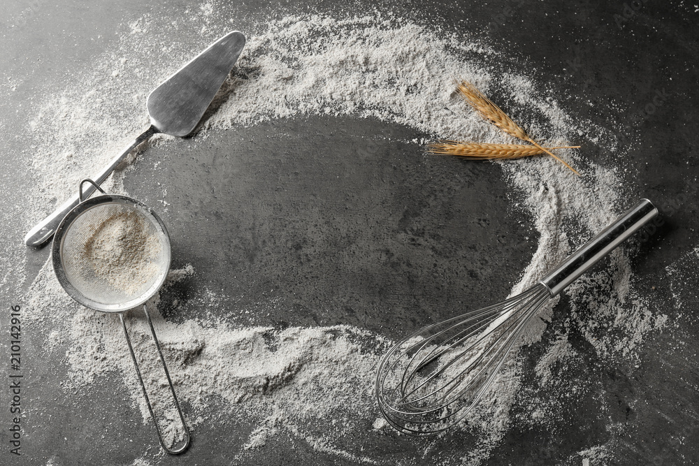 Composition with scattered flour and utensils on grey background