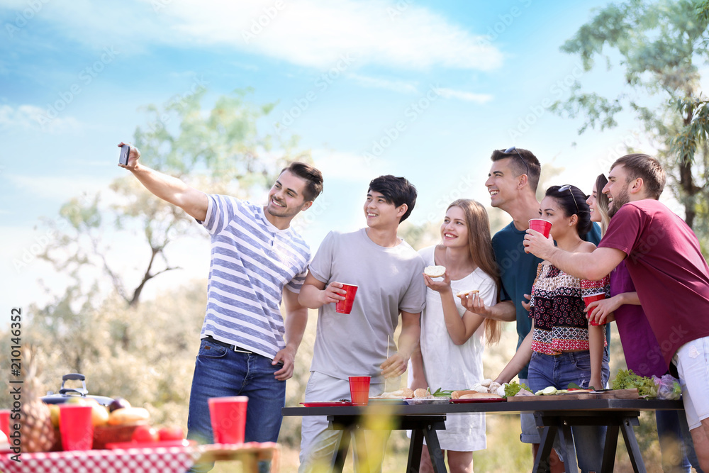 Young people taking selfie while having barbecue party in park