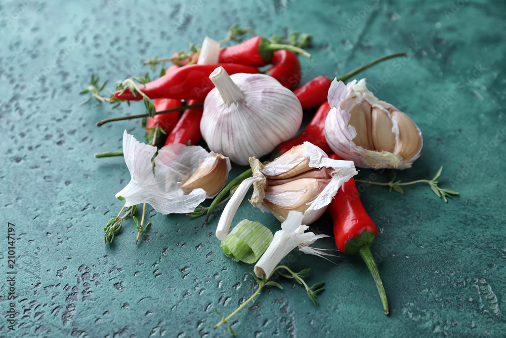 Fresh garlic, thyme and chili peppers on color textured background