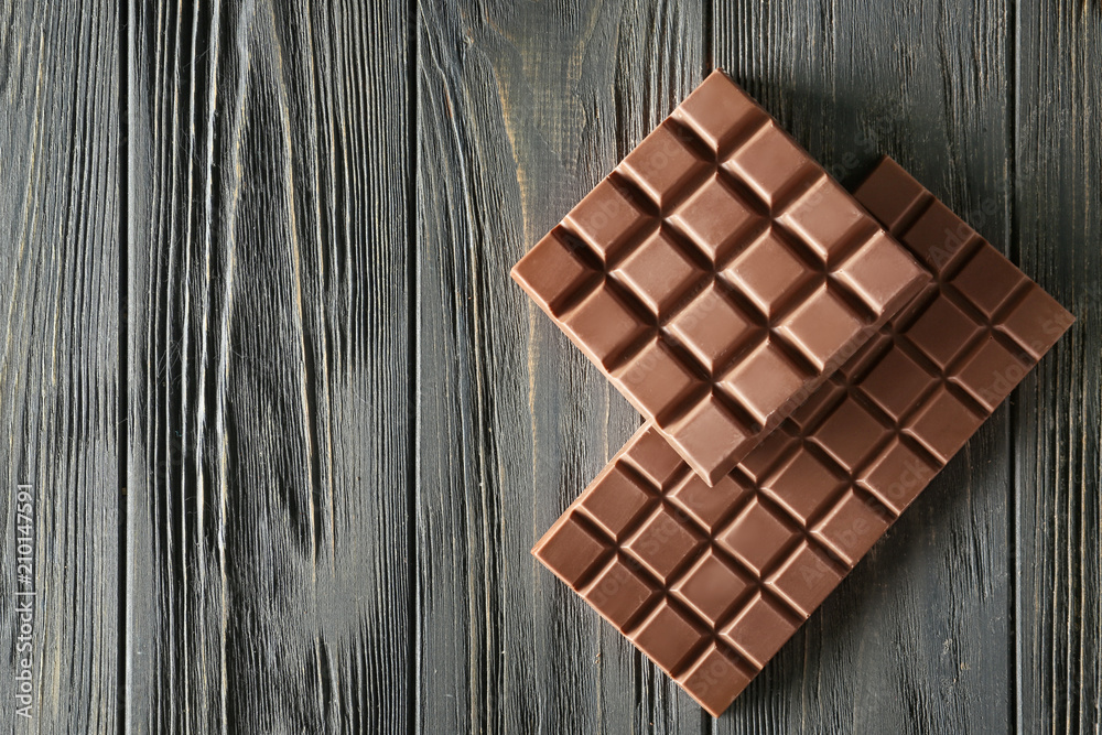 Tasty milk chocolate bars on wooden background