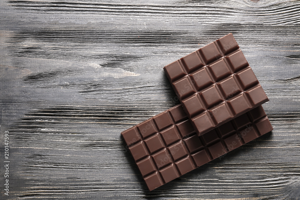 Tasty milk chocolate bars on wooden background