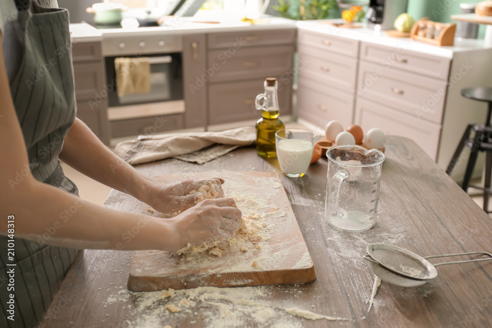 Woman making dough for bakery on table in kitchen