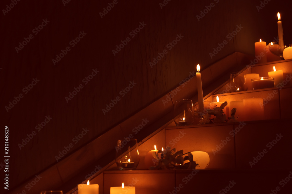 Burning wax candles on stairs in darkness