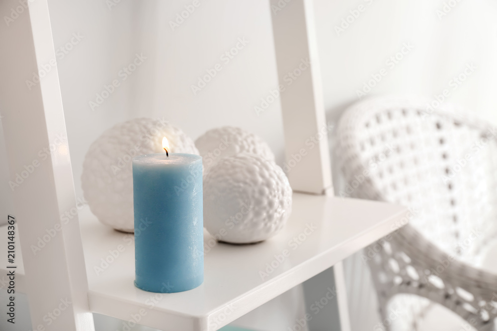 Burning wax candle on shelf