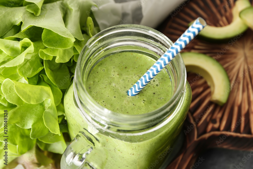 Mason jar with tasty smoothie and ingredients on table, closeup