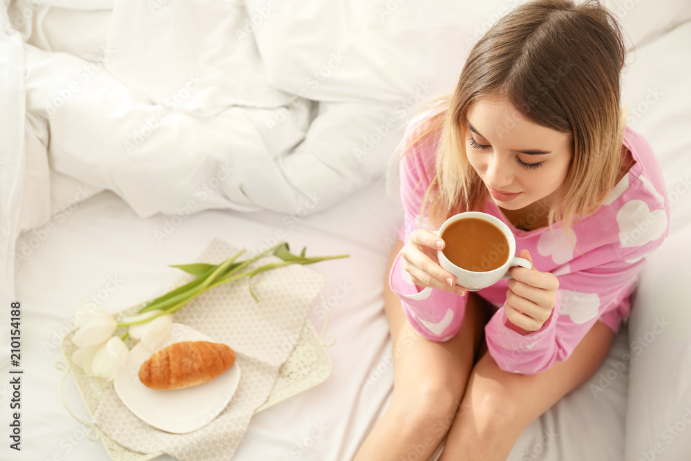 Morning of beautiful young woman drinking hot coffee in bedroom