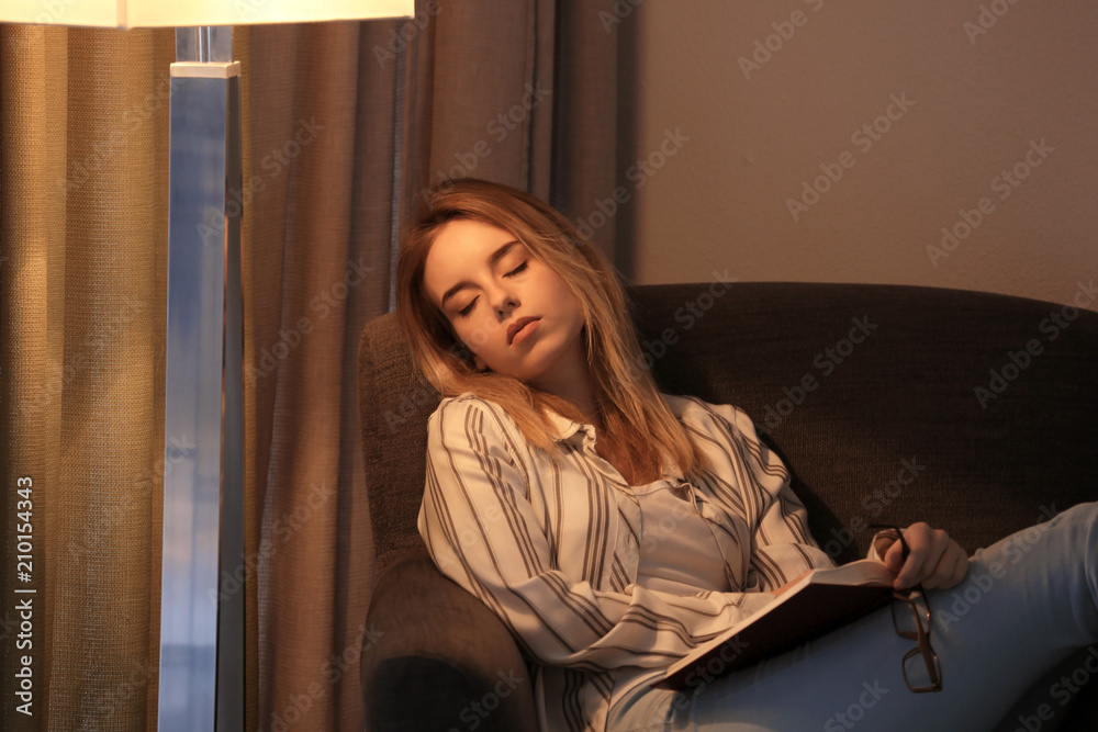 Young woman sleeping in armchair with book