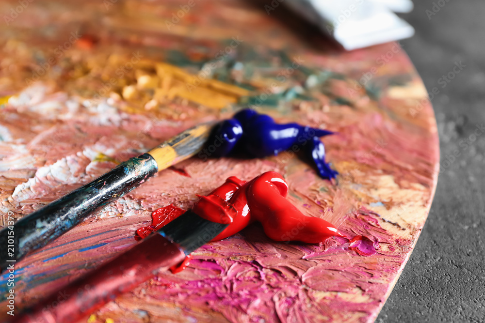 Brushes with paints on wooden palette, closeup