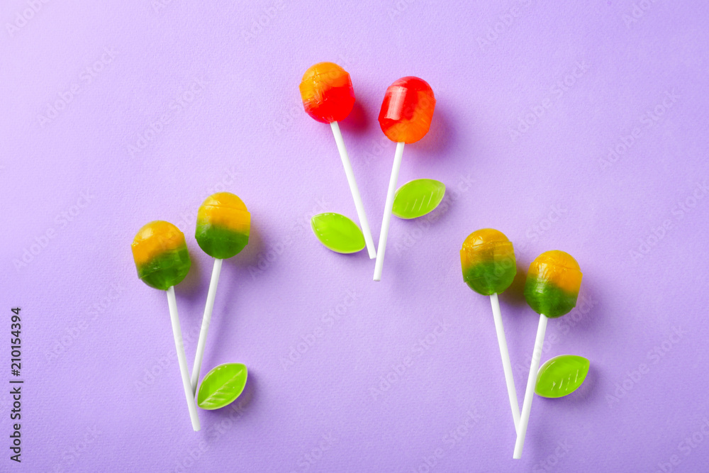 Tasty lollipops with candies on color background