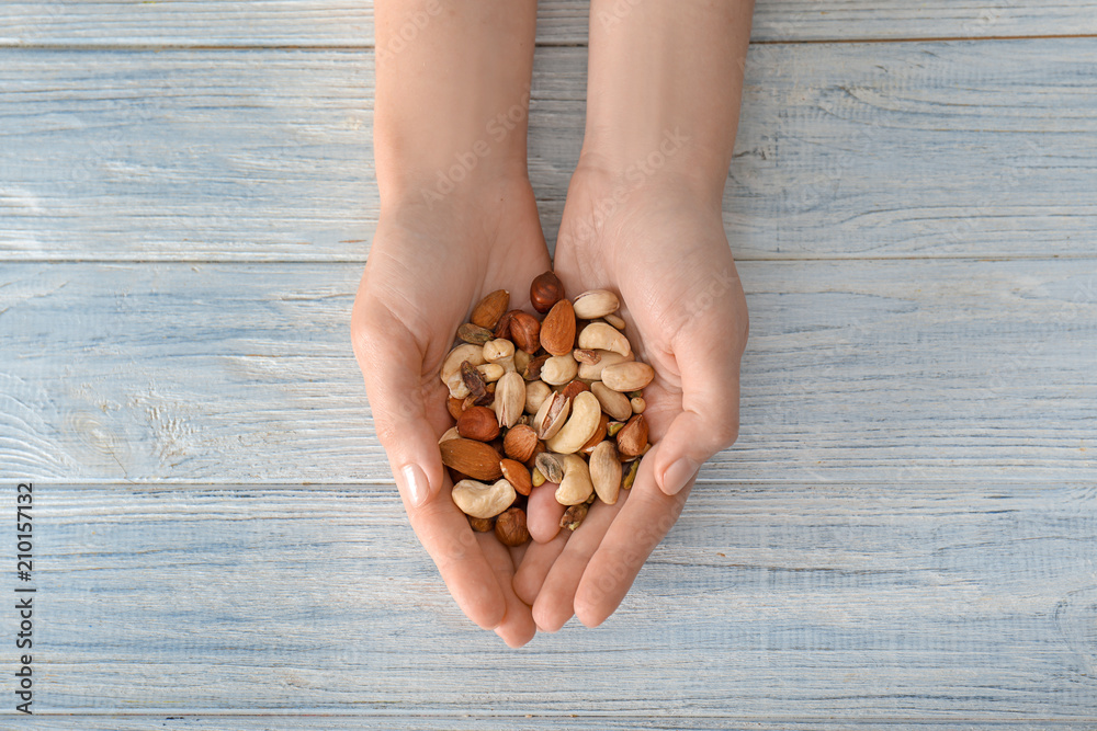 Woman holding different nuts on wooden background