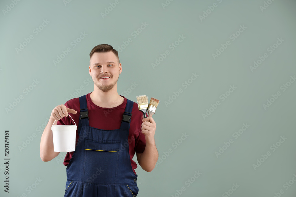 穿着制服的男画家，带刷子和彩色背景的颜料桶