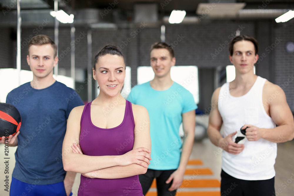 Sporty girl with group of athletes in gym