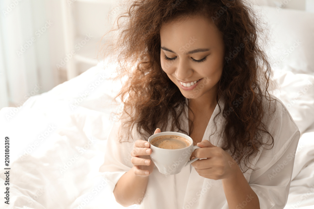 Morning of beautiful African-American woman drinking coffee at home