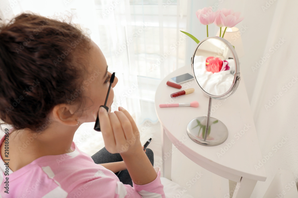 Beautiful African-American woman applying makeup in morning