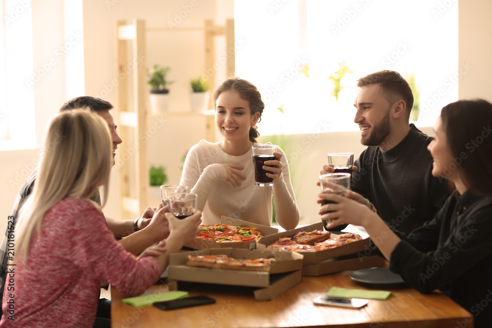 Young people eating pizza at table indoors