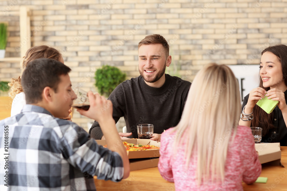 Young people eating pizza at table indoors